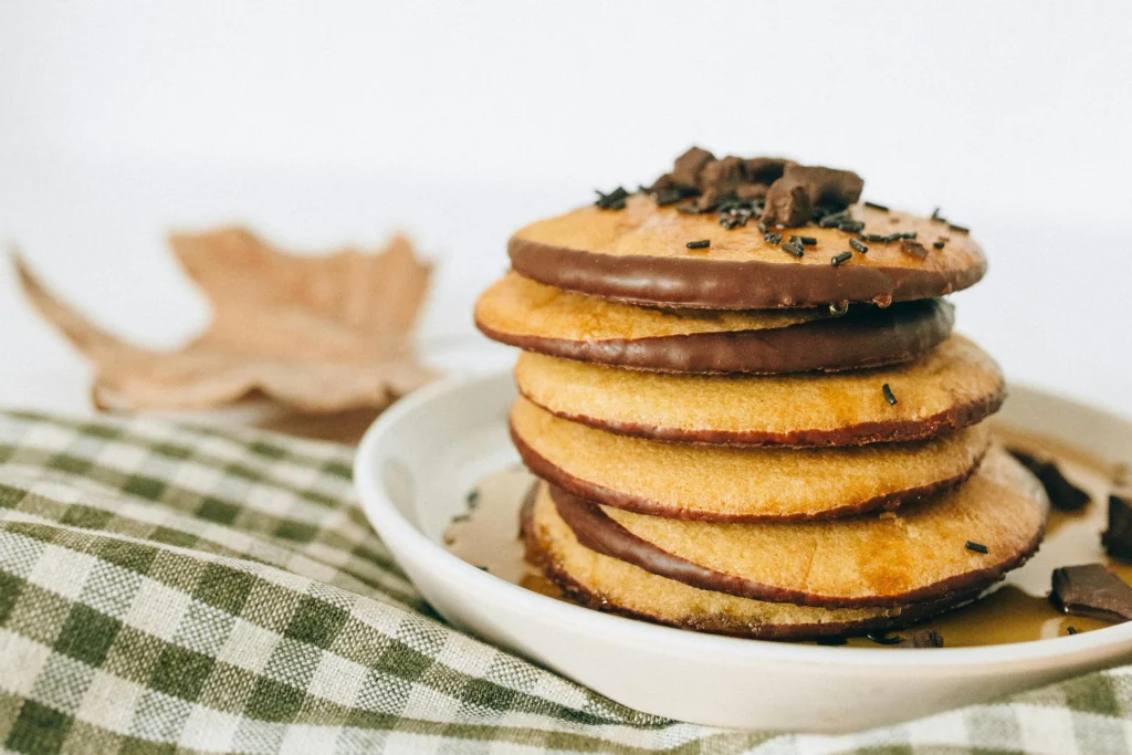 A stack of chocolate chip pancakes with a maple leaf decoration